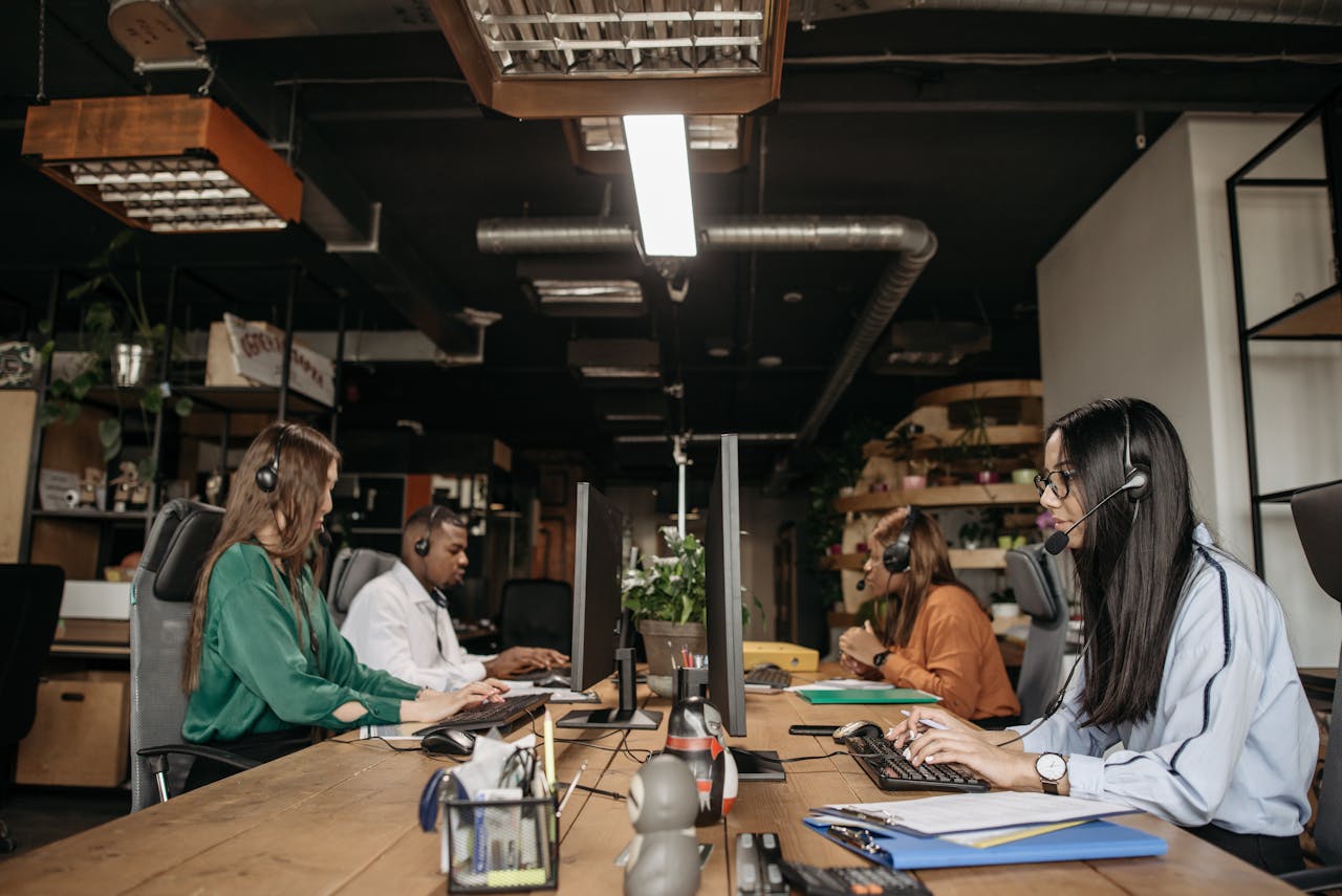 A mixed-gender team working at a call center desk, focusing on customer service tasks.